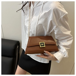 Detail view of caramel brown leather handbag with gold M-buckle and elegant chain strap