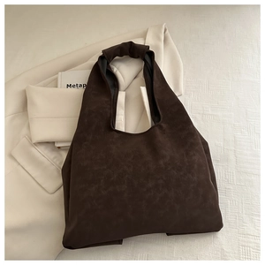 Close-up of deep brown suede tote bag featuring a minimalist bow design and textured finish