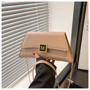 Detail of a beige trapezoid handbag with a gold M buckle and fine chain strap