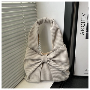 Détail d'un sac cabas en velours côtelé beige avec un grand nœud 3D décoratif et texture côtelée