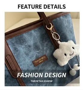 Close-up of blue denim tote bag with brown leather trim and plush cloud charm detail