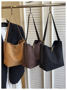 Detailed view of three faux suede bucket bags with gold locks in brown, dark coffee, and black