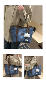 Detail of blue denim tote bag featuring brown leather trim and cute plush cloud charm