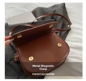Detail view of the brown leather saddle bag with its metal magnetic buckle closure