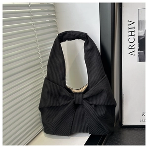 Détail d'un sac à main en velours côtelé noir avec un grand nœud et une texture côtelée