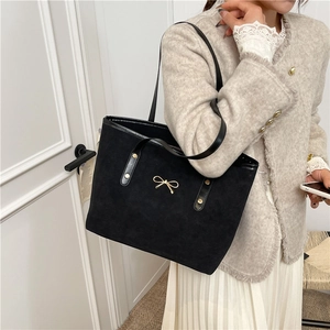 Minimalist black matte faux leather shoulder tote bag with golden bow hardware detail