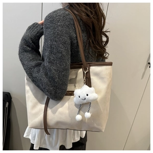 Detail of minimalist tote bag with metal nameplate and cute plush cloud keychain charm