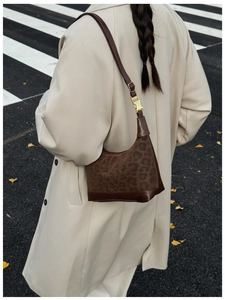 Close-up of leopard print shoulder bag with brown leather strap and gold metal buckle