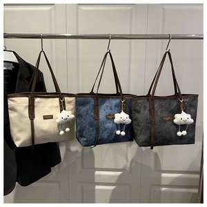 Detailed view of large tote bags in beige, blue, and grey with plush cloud charms