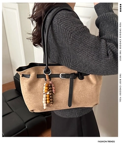 Macro view of khaki suede tote bag with black leather trim and ethnic beaded charm