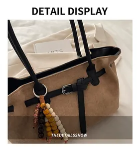 Detail of brown suede tote bag with black leather strap and colorful wooden bead charms