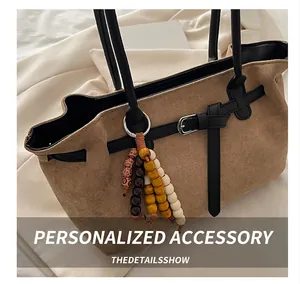 Detail view of large brown suede tote bag with black leather handle and beaded ornament