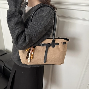 Retro brown suede tote bag with black leather straps and ethnic bead charm on a model