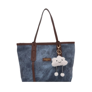 Blue denim tote bag with brown leather straps and a cute plush cloud charm detail