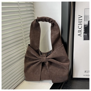 Detail of a coffee brown bow-shaped tote bag with velvety texture in natural lighting