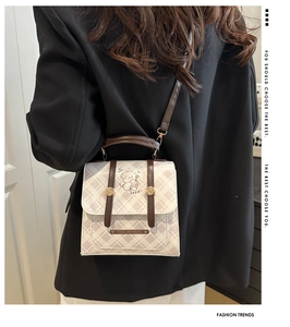 Détail du sac à bandoulière à carreaux avec illustration de chien sur un blazer noir