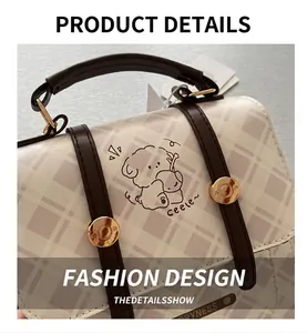 Detail of checkered small square bag featuring cartoon dog print and leather handle