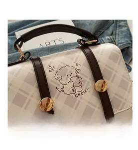 Detail of checkered small square bag featuring cartoon dog print and leather handle