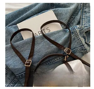 Detail of adjustable brown leather strap with gold buckle on plaid cartoon sheep bag