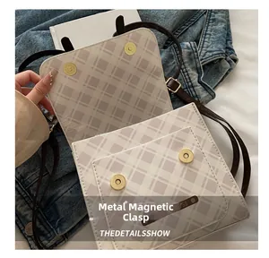 Detail of checkered square crossbody bag featuring hardware magnetic snap closure and strap
