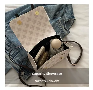 Detail of checkered bag interior with magnetic gold buckles and brown strap