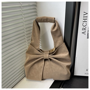 Detail of khaki vintage pleated handbag with large bow and distressed leather texture