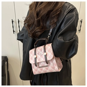 Détail d'un mini sac à dos à carreaux roses avec poignée en cuir brun et boucle dorée