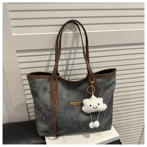 Close-up of washed gray tote with leather handles and a plush cloud charm accessory