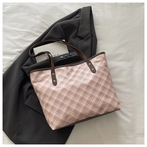 Top view of large checkered tote bag with brown handles and gold rivets on a fabric background
