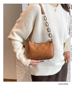 Close-up of retro brown shoulder bag with textured faux leather and resin chain link