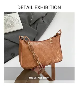 Close-up of brown textured leather bag with stylish resin and gold metal link chain