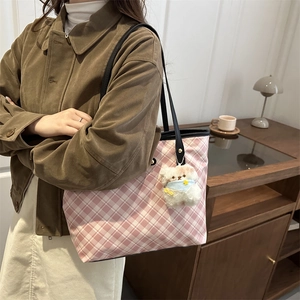 Pink plaid tote bag with black leather straps and plush puppy charm on female model
