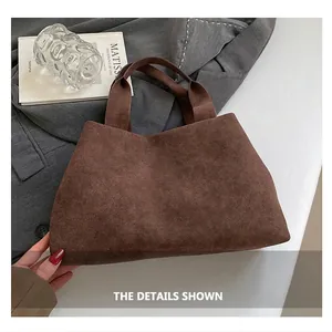 Detail of dark brown suede tote bag on a grey suit with minimalist artistic props