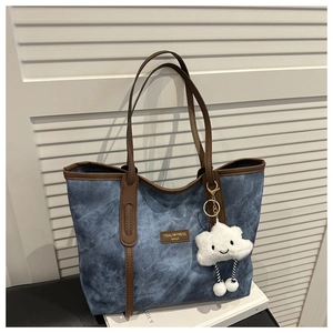Detail of retro washed blue denim tote with brown leather straps and cloud plush charm