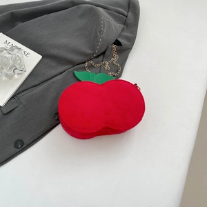 Detail of red cherry crossbody bag with green leaf accents and gold chain strap