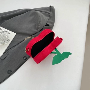 Detail of creative cherry-shaped crossbody bag with red frosted finish and gold chain