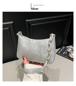 Close-up of silver textured shoulder bag featuring white acrylic chain and golden hardware