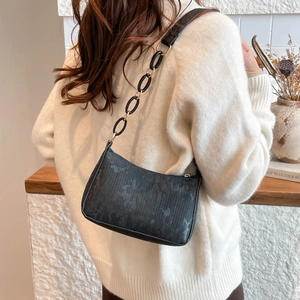 Minimalist black baguette shoulder bag with vertical stripe pattern and metal chain strap