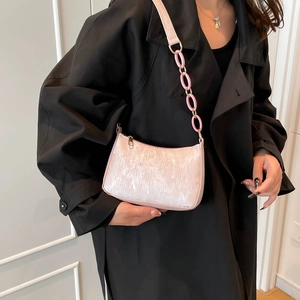 Chic pale pink underarm bag with decorative chain link and metallic zipper on black coat
