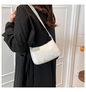 Close-up of minimalist white shoulder bag with vertical texture and metal zipper detail