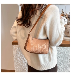 Detail of warm brown vertical texture shoulder bag with metal zipper and leather strap