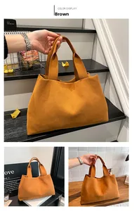 Detailed view of a brown suede minimalist tote bag featuring integrated top handles