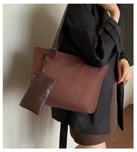 Detail of a dark brown suede tote bag with a matching small pouch on a black suit