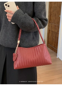 Détail d'un sac à main rouge en cuir tressé avec breloque cœur et bandoulière
