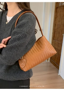 Détail du sac sous l'aisselle en cuir tressé caramel avec un charm en forme de feuille rétro