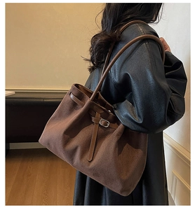 Detail of dark brown suede tote bag featuring a leather strap and metallic buckle