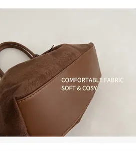 Detailed stitching on dark brown suede and leather tote bag with office accessories