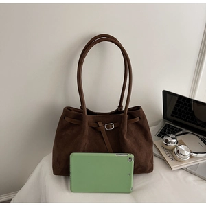 Macro shot of dark brown suede tote bag with slim handles and silver buckle detail