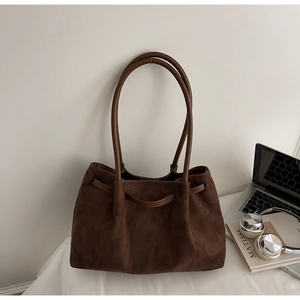 Detail of dark brown suede tote bag with drawstring, laptop and headphones setup