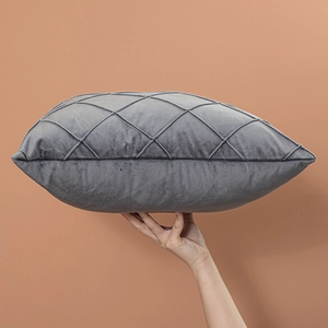 Dark gray velvet pillow with diamond quilted pattern and plush stuffing shown in hand